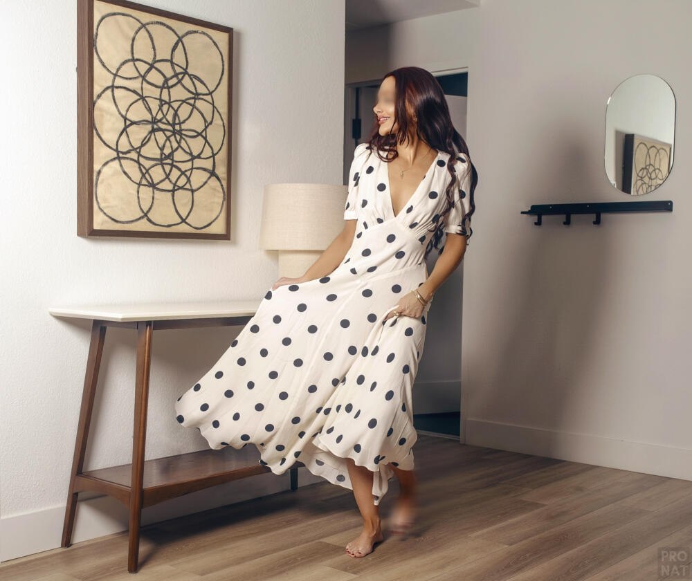 Caterina Fontana dances in her incall wearing a white flowy polka dot dress